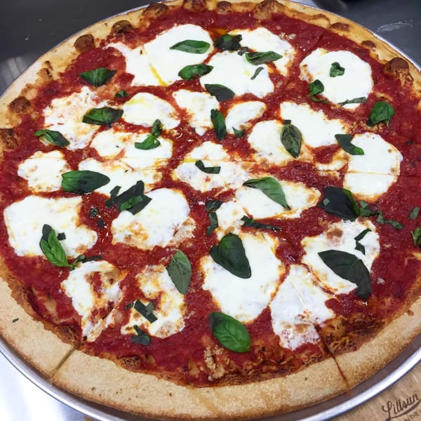A whole Marc's Pizzeria and Grill Margherita pizza with fresh mozzarella, tomato sauce, and basil.